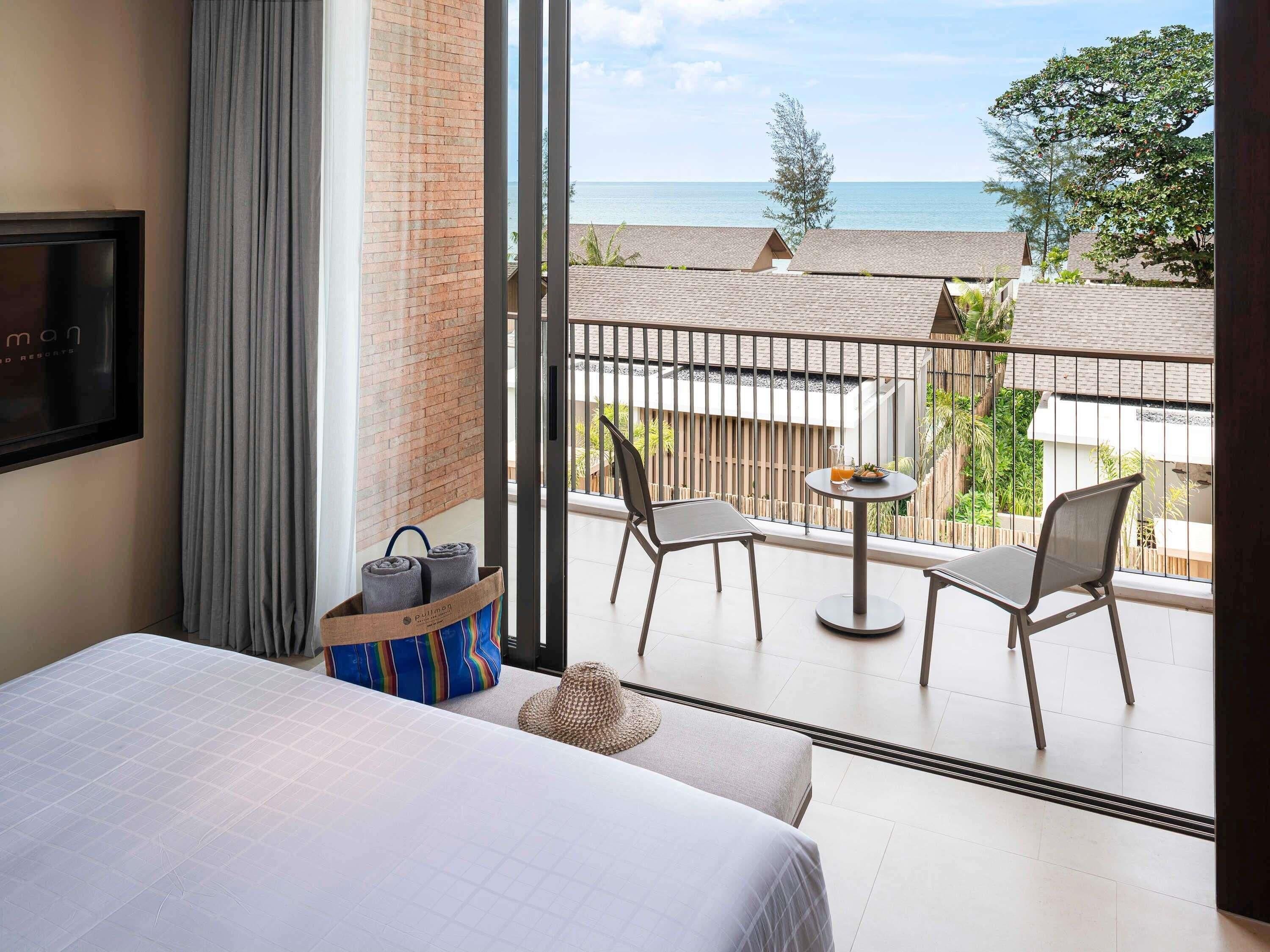Een hotelkamer met balkon, een bed, een televisie en uitzicht op zee.
