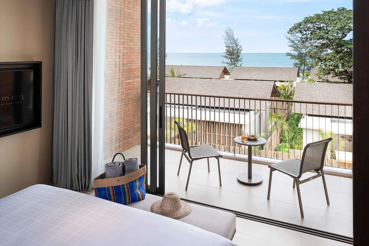 Une chambre d’hôtel avec un balcon, un lit, une télévision et une vue sur la mer.