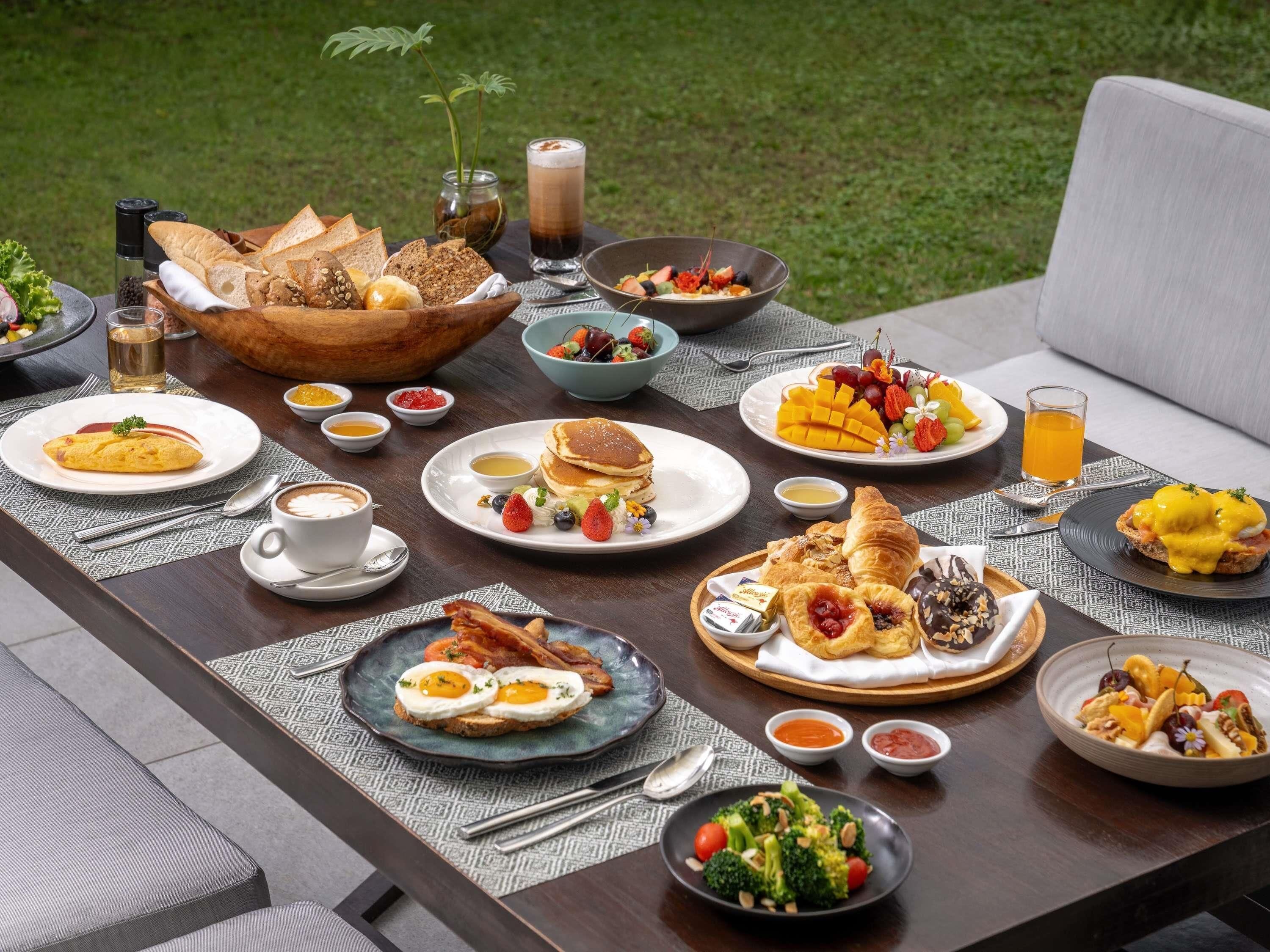 Ein reichhaltiges Frühstücksbuffet mit verschiedenen Speisen, darunter Eier, Pfannkuchen und Früchte.