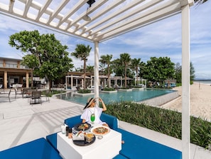 Un espace de restauration situé au bord de la piscine, avec des sièges en plein air, une piscine et une vue sur la plage.