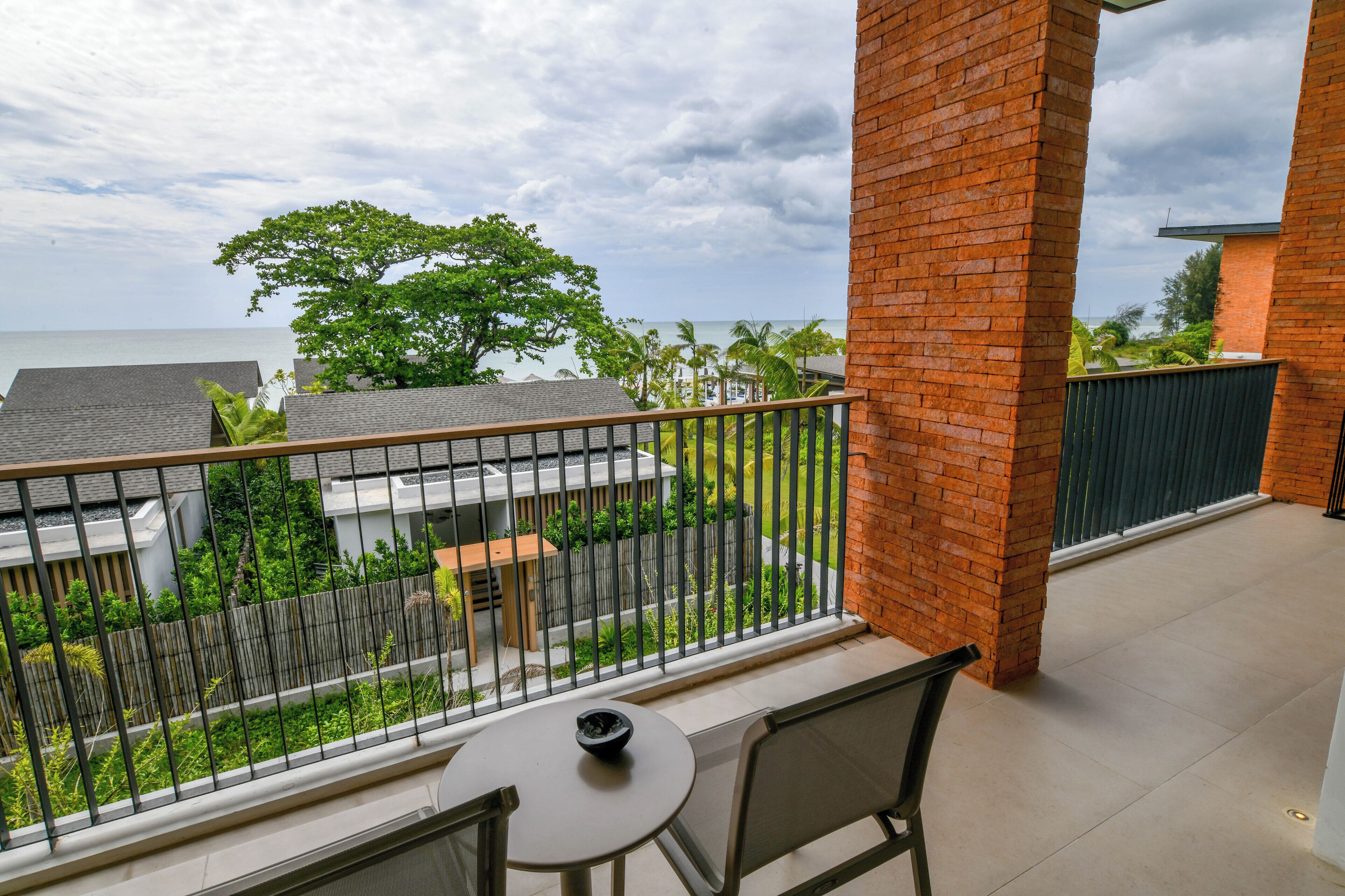 Un balcon avec une table et des chaises, donnant sur un quartier résidentiel et offrant une vue sur la mer.