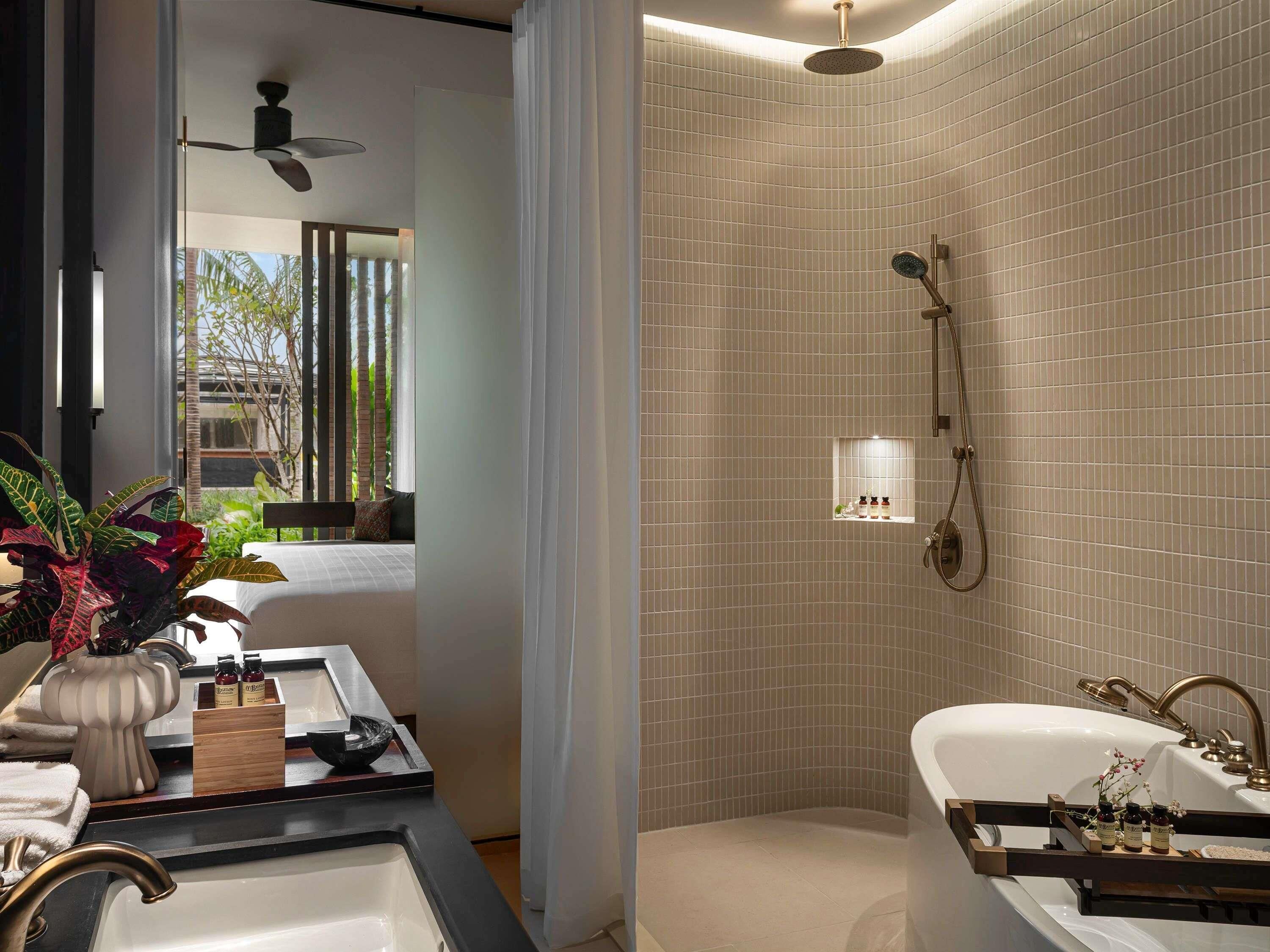 Une salle de bain moderne équipée d’une baignoire, d’une douche et d’un espace coiffeuse avec des articles de toilette.