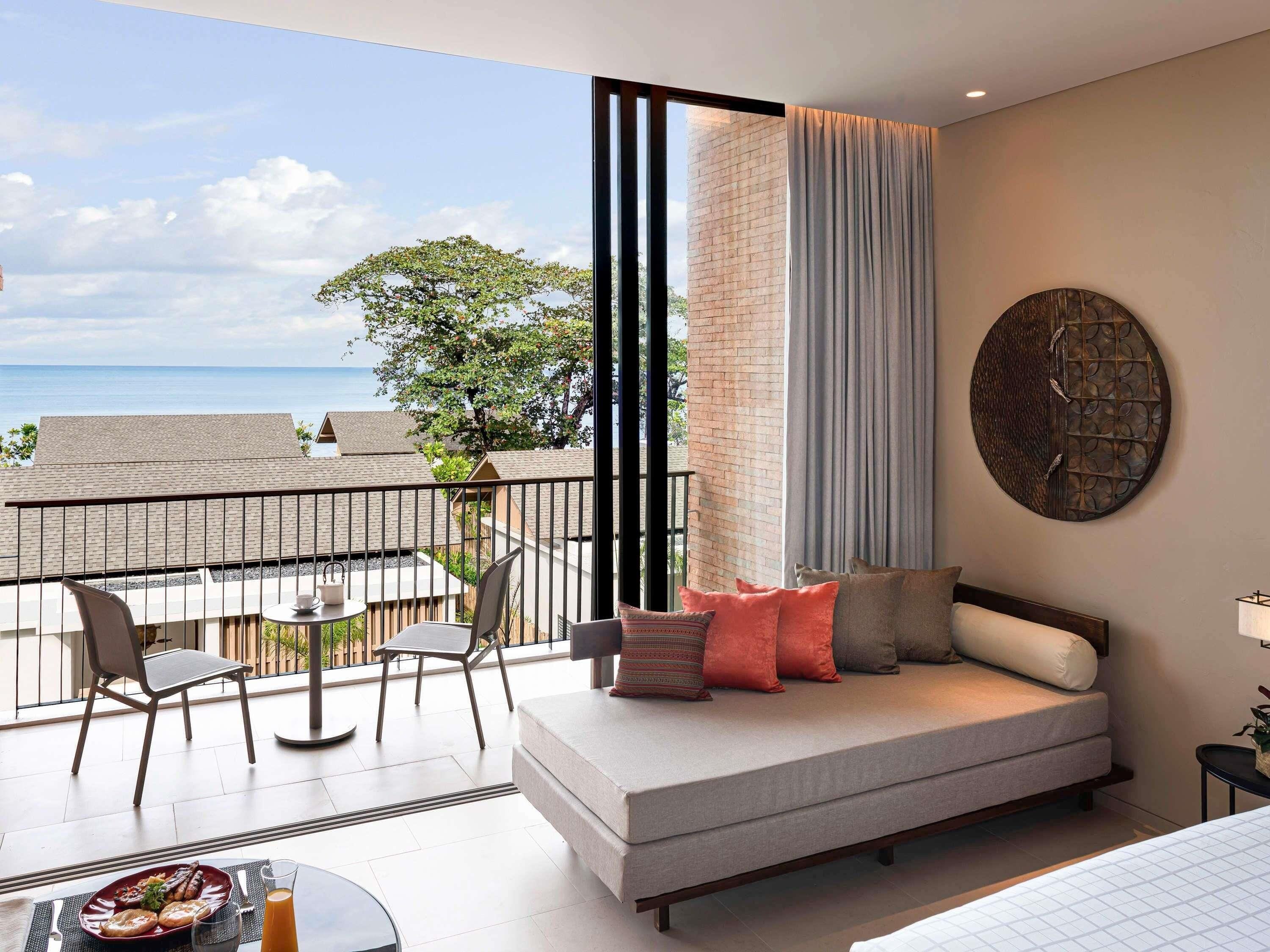 A balcony with a sofa, chairs, and a dining table with breakfast items.