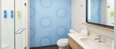 Un baño moderno con cabina de ducha de vidrio, inodoro y tocador con lavamanos.