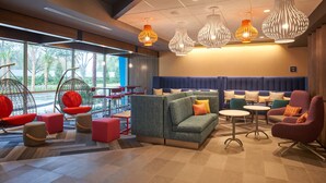 A modern lounge area with a sofa, chairs, and hanging lights. - Tru by Hilton Jacksonville South Mandarin (Jacksonville)
