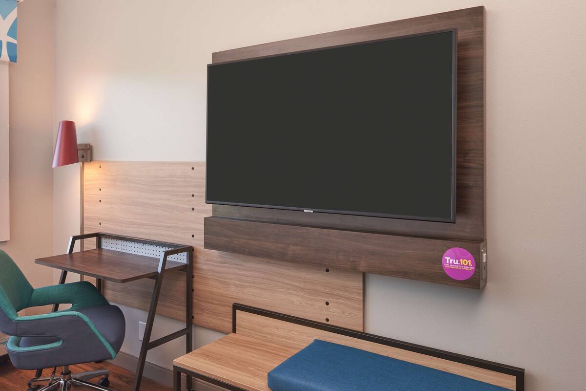 A modern room with a mounted TV, a desk, and a comfortable seating area.