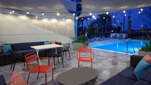 An outdoor patio with a pool, seating area, and string lights. - Tru by Hilton Jacksonville South Mandarin (Jacksonville)