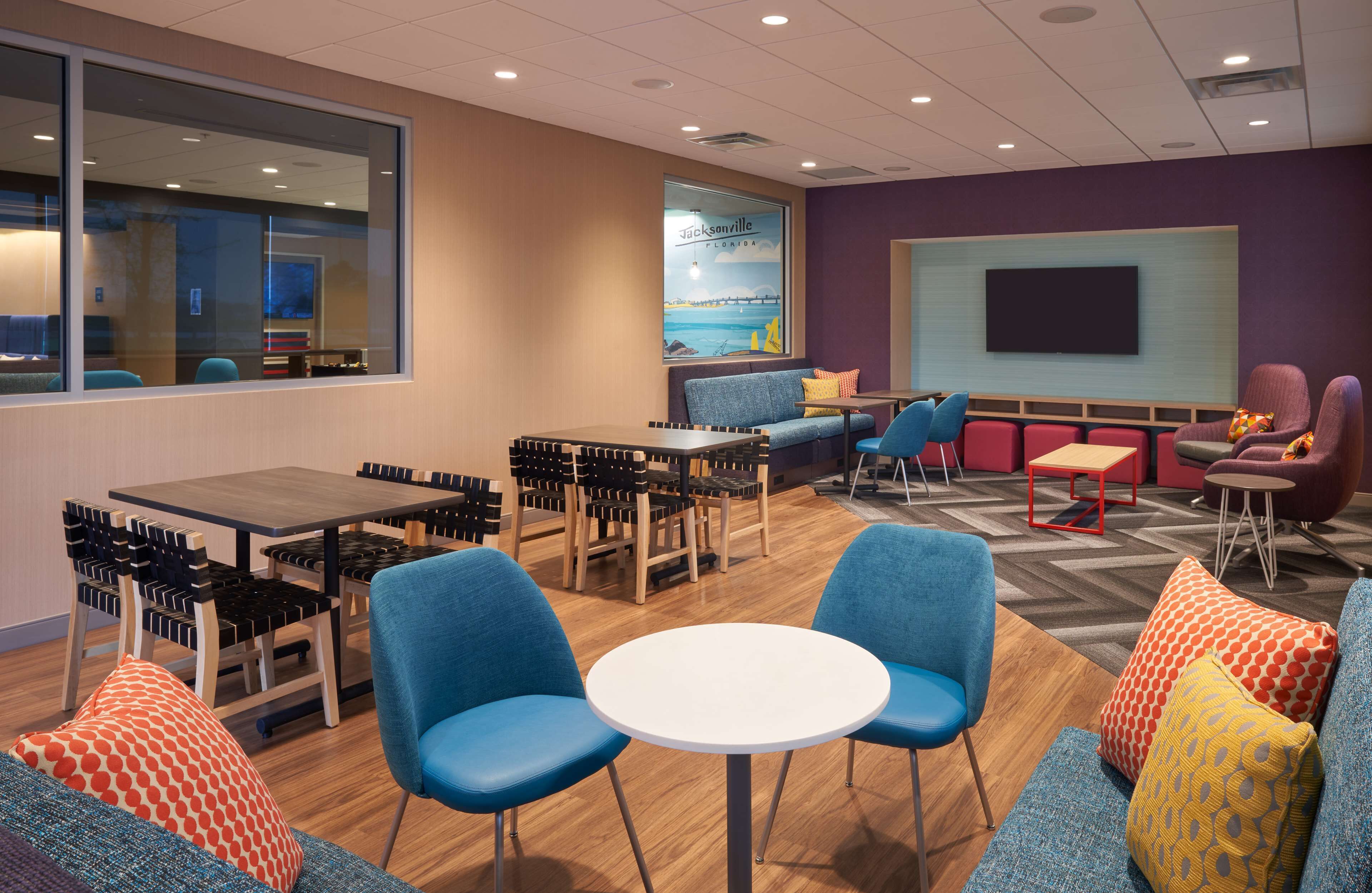 A modern lounge area with seating, tables, and a large screen wall.