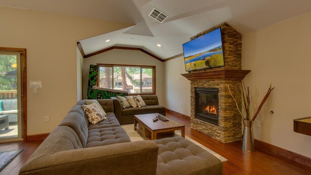 A living room with a stone fireplace, a large flat-screen TV, a sectional sofa, and a wooden coffee table. - Air Conditioning, Shuffleboard, Walk to Heavenly/ Casinos/ Lake, Grill, Wifi – Tahoe Woods Luxury (South Lake Tahoe)