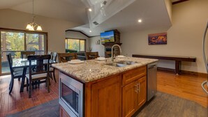 A modern kitchen with a granite countertop, stainless steel appliances, and a dining area with wooden chairs. - Air Conditioning, Shuffleboard, Walk to Heavenly/ Casinos/ Lake, Grill, Wifi – Tahoe Woods Luxury (South Lake Tahoe)
