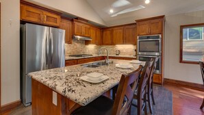 A modern kitchen with wooden cabinets, stainless steel appliances, and a granite countertop. - Air Conditioning, Shuffleboard, Walk to Heavenly/ Casinos/ Lake, Grill, Wifi – Tahoe Woods Luxury (South Lake Tahoe)