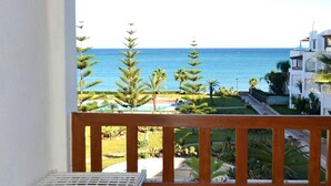 Un balcon avec vue sur la mer, les palmiers et une piscine.