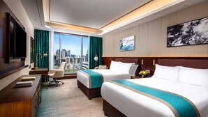 A hotel room with two beds, a desk, a chair, a TV, and a large window offering a city view.