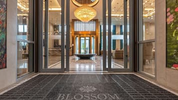Eine Hotelhalle mit einem prunkvollen Kronleuchter, einem Empfangstresen und einem Teppich mit dem Namen des Hotels.