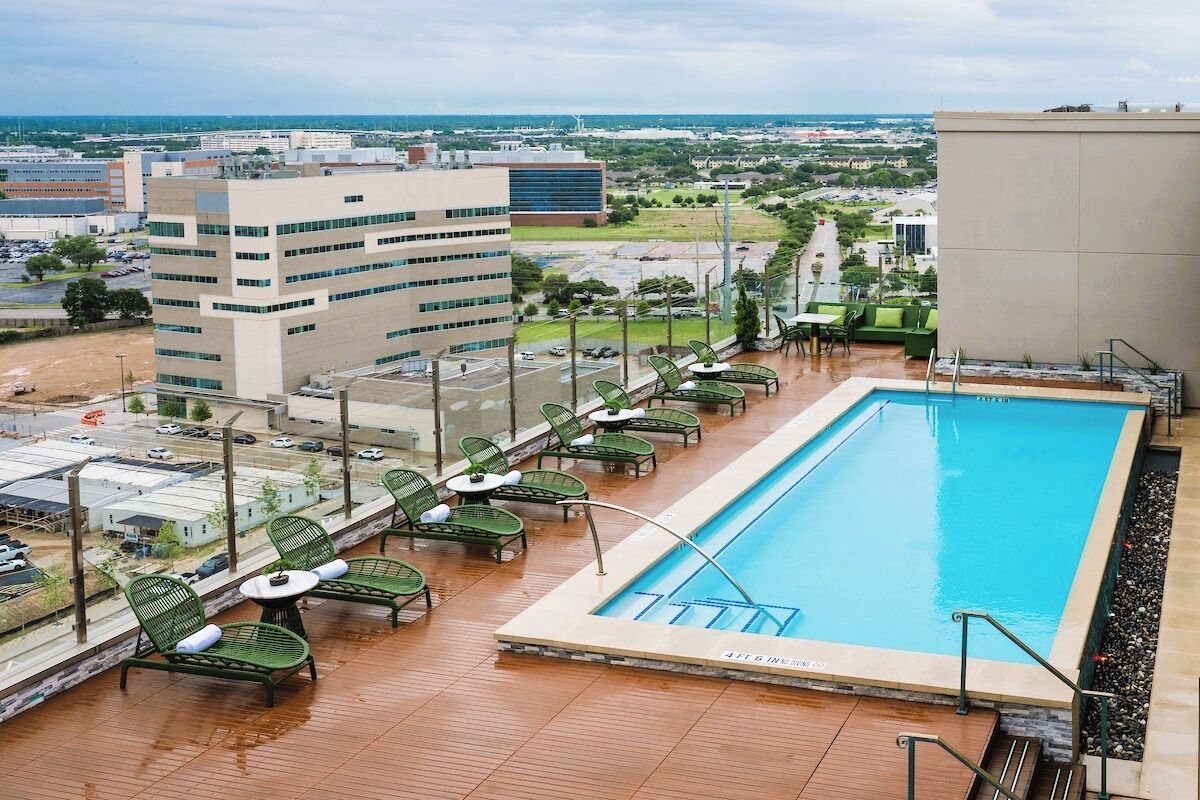 A rooftop pool with lounge chairs and a view of the cityscape.