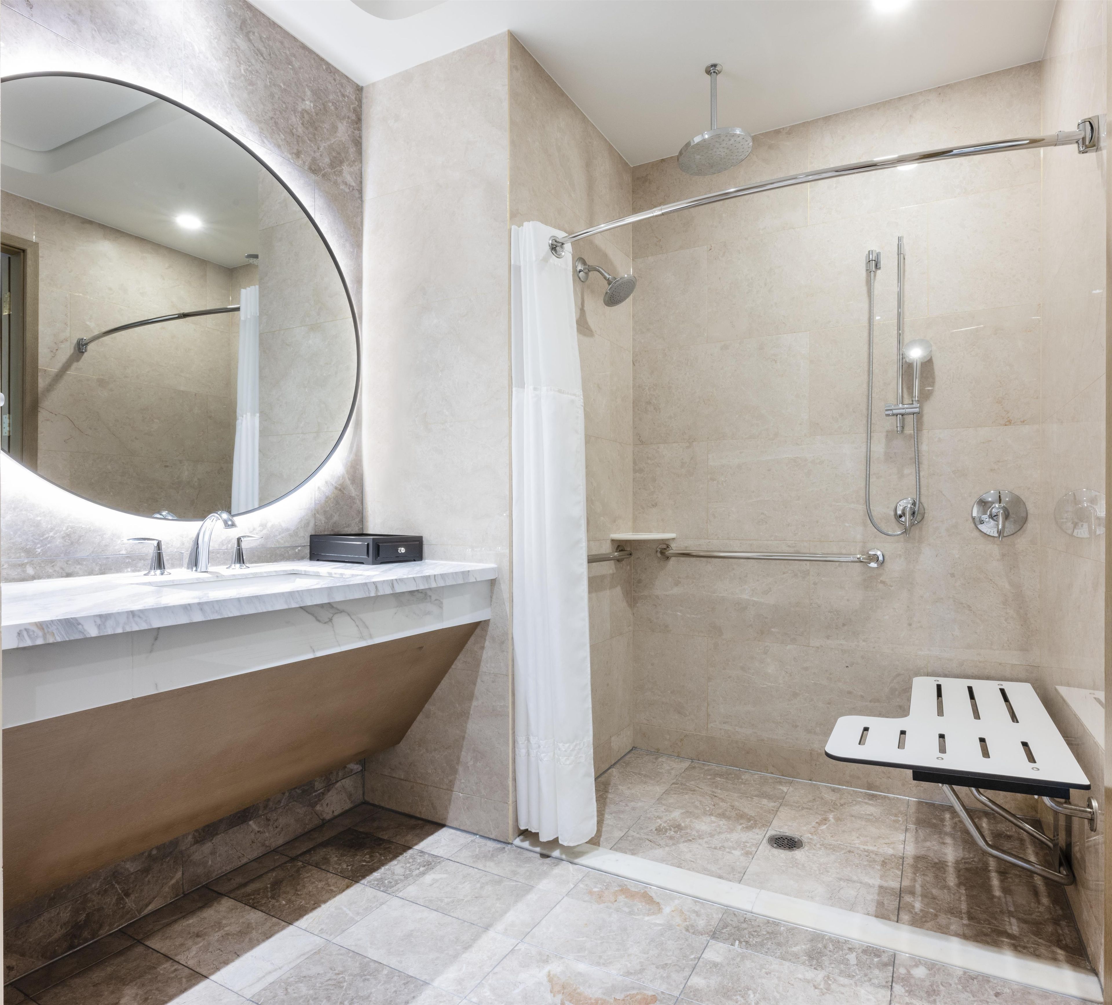 A modern bathroom with a shower, a bathtub, and a vanity with a mirror.