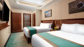Quarto de hotel com duas camas, televisão, um quadro e piso coberto por carpete.