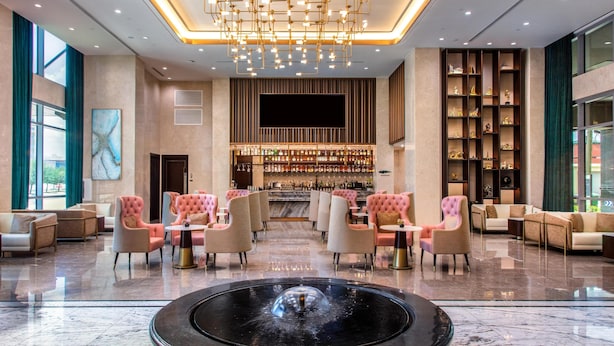 A modern lobby with a bar area, seating arrangements, and a decorative fountain.