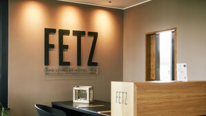 Een hotel receptie met een balie, stoelen en een wandbord waarop staat 