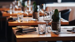 Een restaurant met gedekte tafels, hanglampen en potplanten.