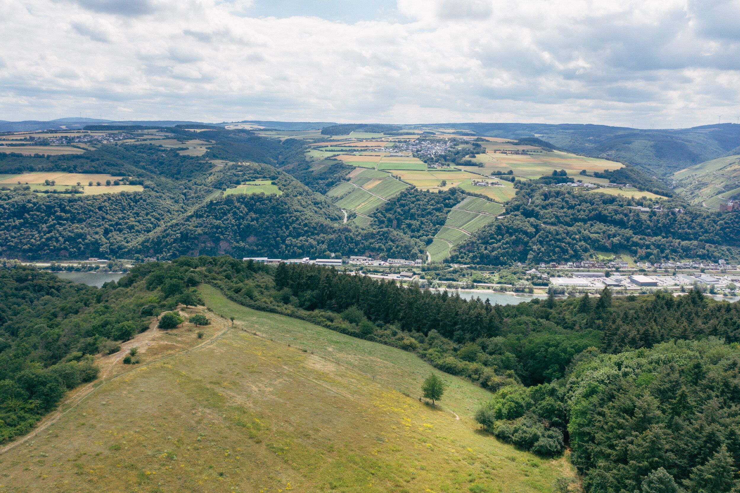 Une vue panoramique d’une vallée avec une petite ville, entourée de collines et de champs.