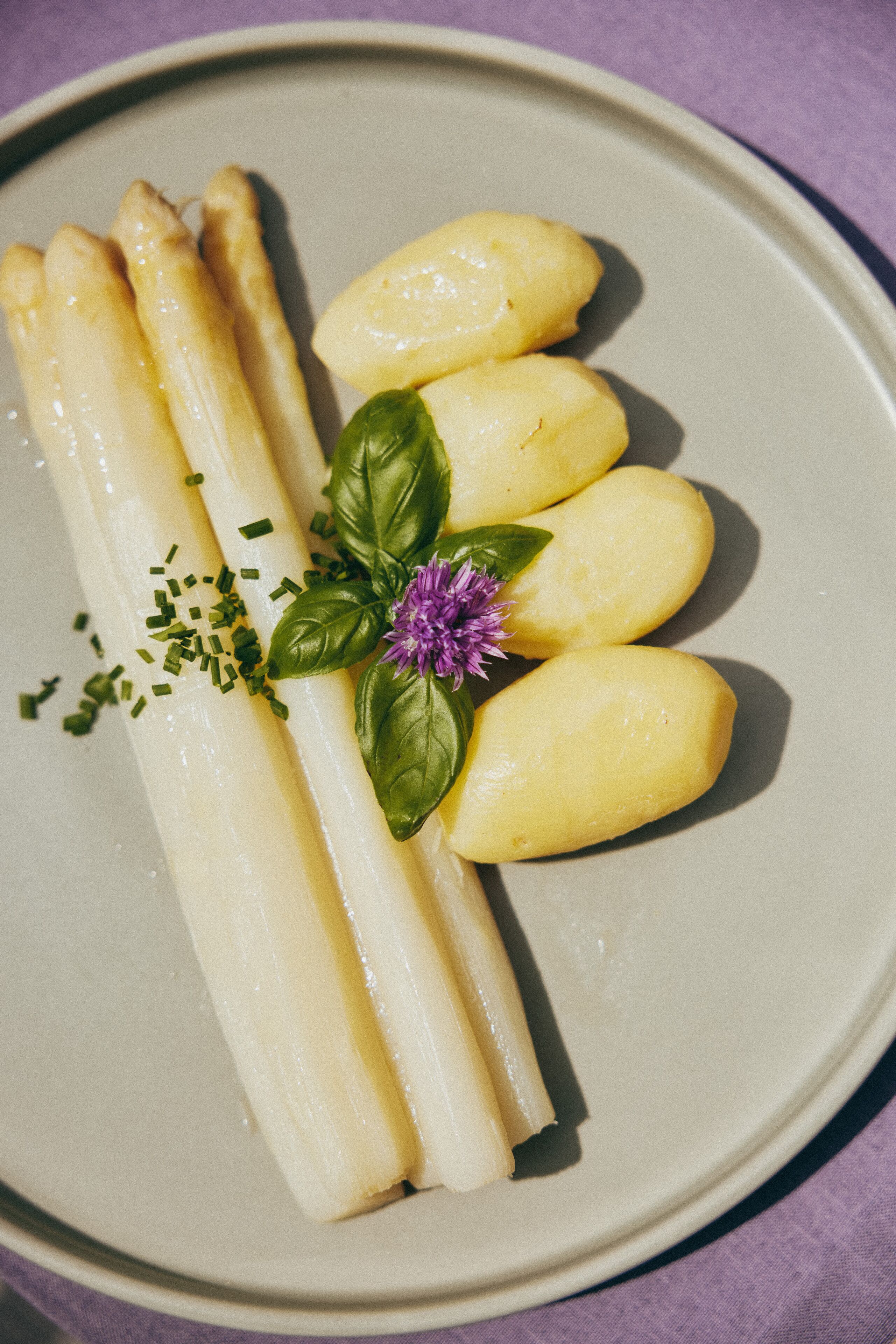 A plate with asparagus and potatoes garnished with basil and chives.