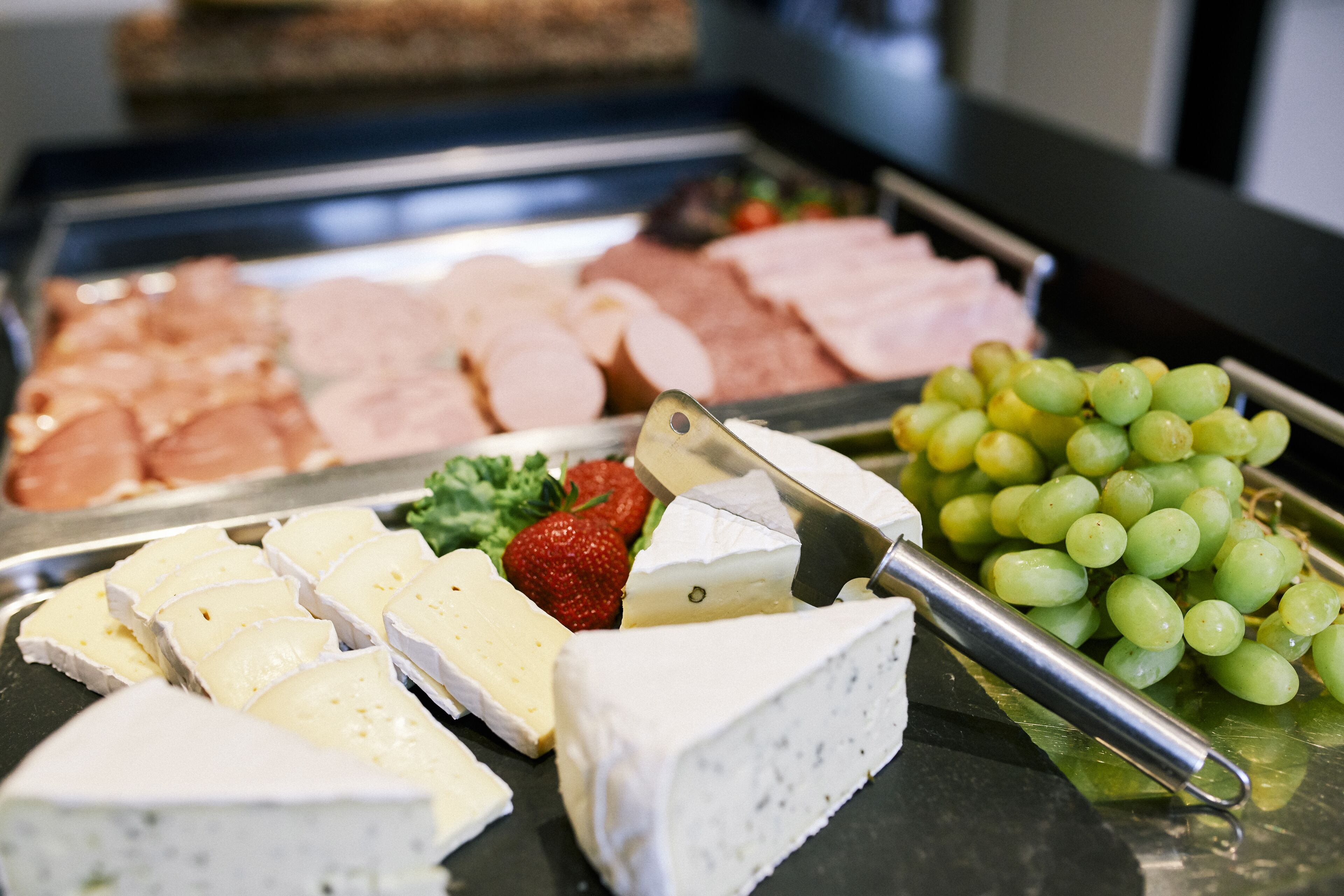 A cheese and fruit platter with various cheeses and grapes.