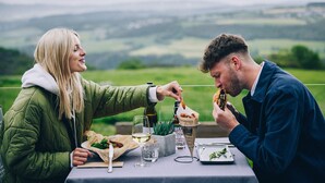 Twee personen dineren buiten met een prachtig uitzicht op de achtergrond.