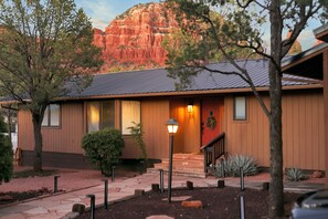 A two-story house with a stone foundation, a dark roof, and a front porch with a light fixture.
