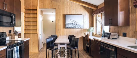 Una cocina moderna con paredes de madera, una mesa de comedor con sillas y electrodomésticos integrados.