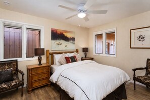 Ein Schlafzimmer mit einem großen Bett, Nachttischen aus Holz, einem Deckenventilator und einem Bild an der Wand.