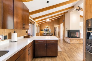 A kitchen with wooden cabinets, a central island, a fireplace, and a ceiling fan.
