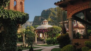 A garden with a gazebo, a bell tower, and a building with a dome.