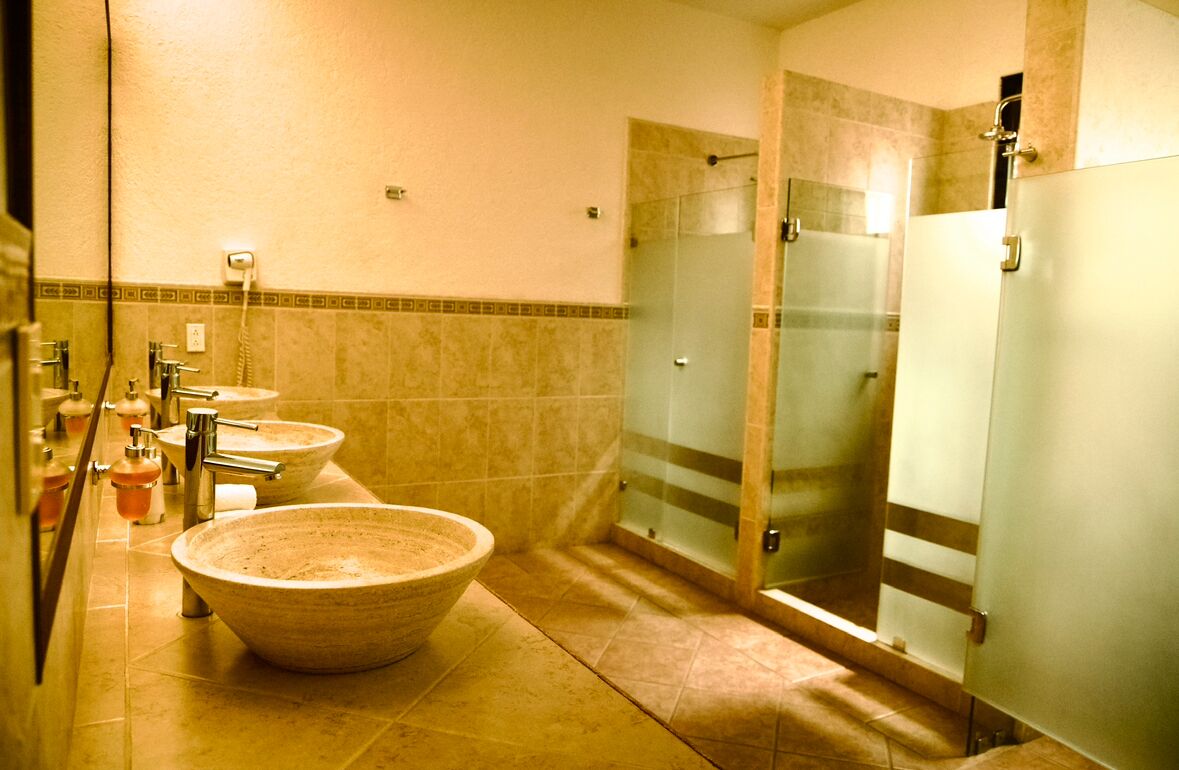 Ein Badezimmer mit drei Waschbecken, einem großzügigen Schüsselwaschbecken und einer Duschkabine aus Glas.