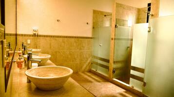 Ein Badezimmer mit drei Waschbecken, einem großzügigen Schüsselwaschbecken und einer Duschkabine aus Glas.