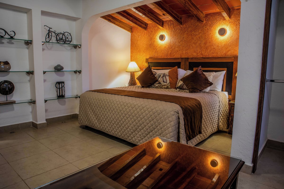 A bedroom with a wooden headboard, a quilted bedspread, and a bedside table with a lamp.