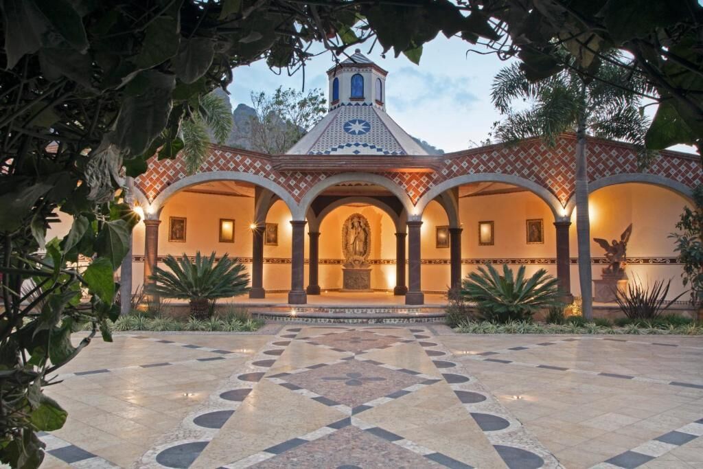 A courtyard with a central statue, surrounded by arches and a tiled floor.