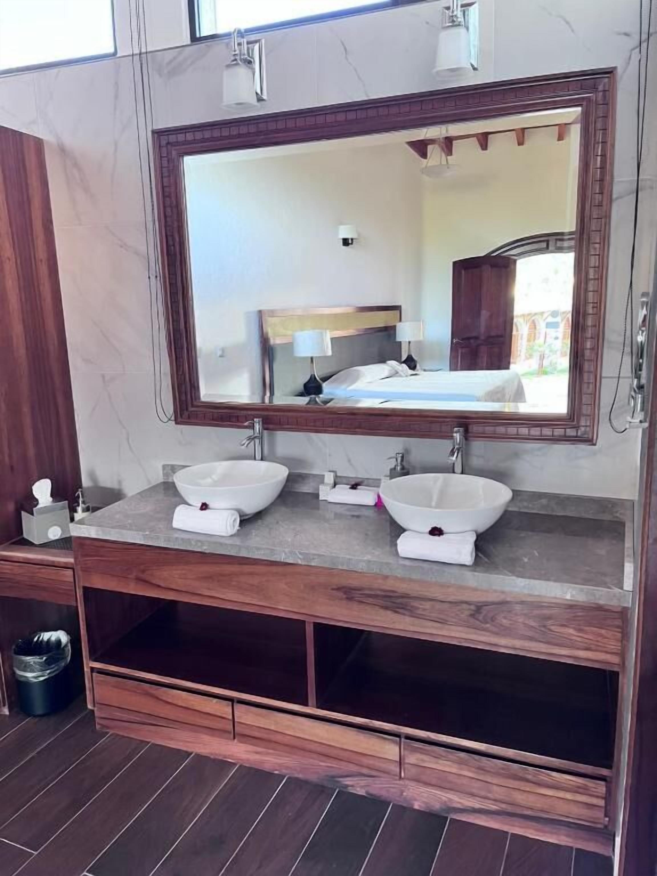 A bathroom with a large mirror, two sinks, and a wooden vanity.
