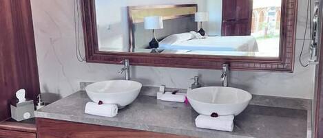 A bathroom with a large mirror, two sinks, and a wooden vanity.