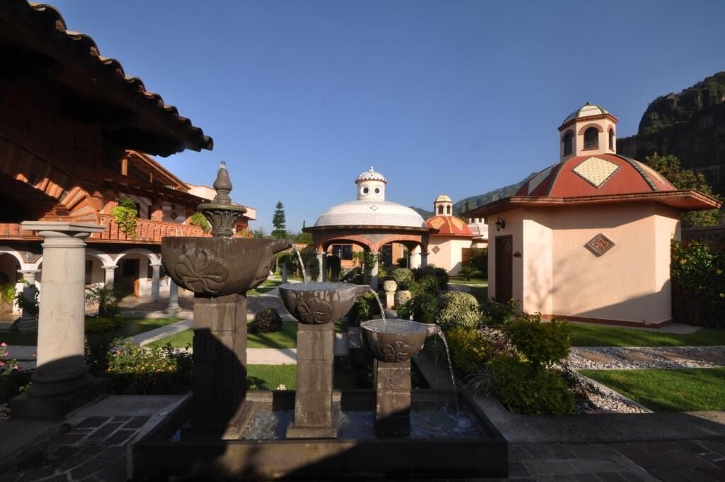 A courtyard with a fountain, a dome-shaped building, and a bell tower.