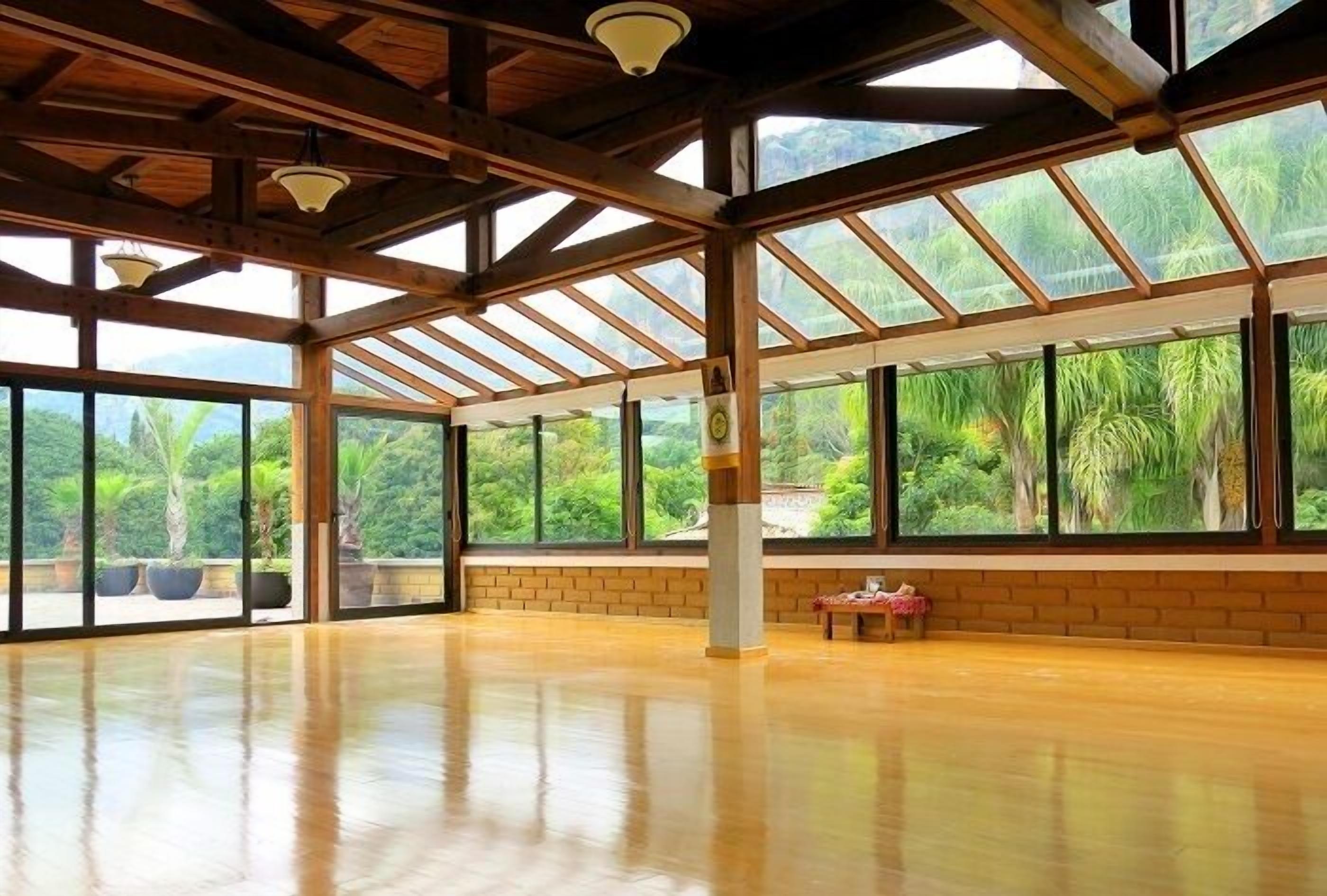 A spacious room with large windows, wooden beams, and a polished floor.