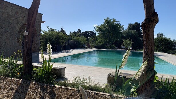 A swimming pool surrounded by trees and a stone wall. - Pyrenean Paradise (Castelnou)