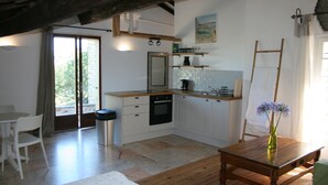 A compact kitchen with white cabinets, a wooden table, and a vase with flowers. - Pyrenean Paradise (Castelnou)