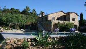 A stone building with a pool, surrounded by greenery and a clear sky. - Pyrenean Paradise (Castelnou)