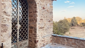 A stone building with a large arched doorway and a metal gate. - Pyrenean Paradise (Castelnou)