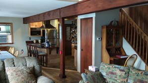 Ein geräumiger Wohnbereich mit einer Holztreppe, ein Essbereich mit Stühlen und eine Küche mit modernen Geräten.