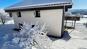 Een huis bedekt met sneeuw, met een witte gevel en een grijs dak.
