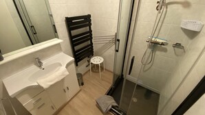 A modern bathroom with a glass shower enclosure, a white sink with a towel, and a black towel rack. - GITE 2 to 5 PERS HAUT JURA PLEINE NATURE (Morbier)