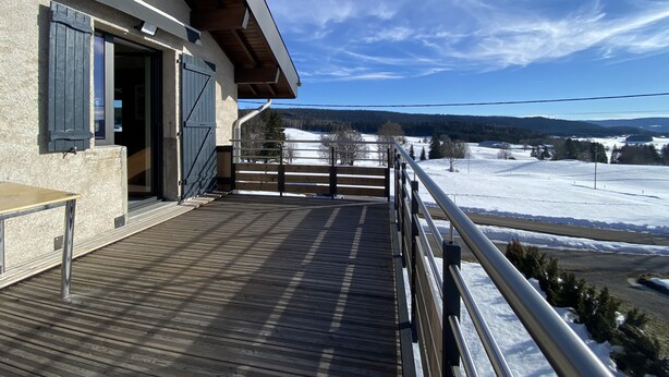 A wooden deck with a metal railing overlooking a snowy landscape. - GITE 2 to 5 PERS HAUT JURA PLEINE NATURE (Morbier)