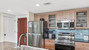 A modern kitchen with stainless steel appliances, wooden cabinets, and a double sink. - Full Kitchen ~ Private Balcony ~ Resort Pool (Miramar Beach)